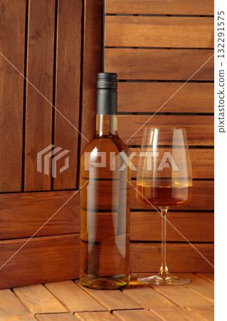 Bottle and glass of white wine on a wooden background. Bottle and glass of white wine on a wooden background. 132291575