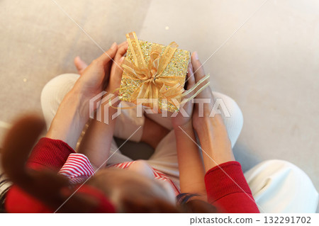 Gift Exchange. Close-up of mother and child holding a beautifully wrapped present. 132291702