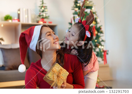Christmas Celebration. A mother and daughter share a joyful moment with a gift. 132291703