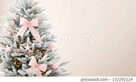 Snow-covered Christmas tree adorned with pink decorations and soft white background for festive ambiance Snow-covered Christmas tree adorned with pink decorations and soft white background for festive ambiance 132292124