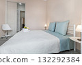 Modern Bedroom Interior with Blue Bedding and White Chair 132292384