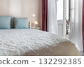 Bright Bedroom Interior with Blue Pillows and Fresh Towels on Bed 132292385