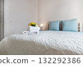 Bright Bedroom Interior with Blue Pillows and Fresh Towels on Bed 132292386