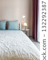 Minimal Bedroom Interior with Blue Pillows and Soft White Bedspread 132292387