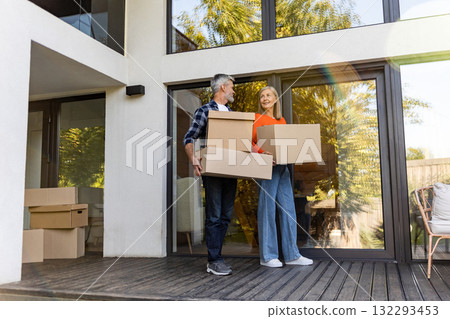 Senior man and woman transporting packed cardboard boxes into new house 132293453