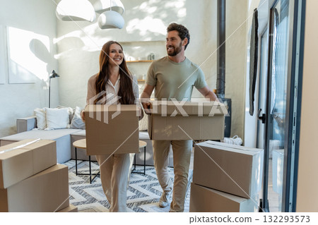 Two people with cardboard boxes entering a house and looking contented 132293573