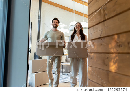 Two people with cardboard boxes entering a house and looking contented 132293574