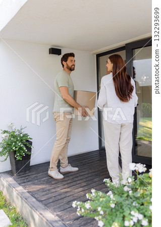 Couple carrying cardboard boxes while moving to a new house Couple carrying cardboard boxes while moving to a new house 132293699