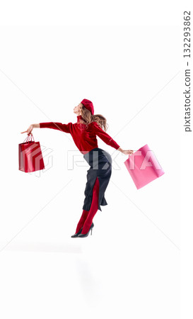 Elegant woman in red sweater and beret holding shopping bags in balanced fashion motion 132293862