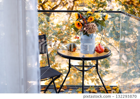 Seasonal floral arrangement in a vintage can on balcony table with gourds, leaves, and a black chair in soft natural light. Micro-retreats, flower therapy, mental wellness, mindful balcony design Seasonal floral arrangement in a vintage can on balcony table with gourds, leaves, and a black chair in soft natural light. Micro-retreats, flower therapy, mental wellness, mindful balcony design 132293870