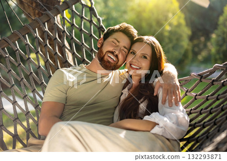 Cute smiling couple enjoying time together while sitting in hammock in the park Cute smiling couple enjoying time together while sitting in hammock in the park 132293871