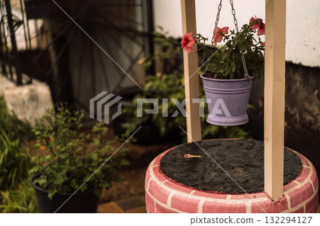Closeup of purple flower pot hanging on decorative garden stand Closeup of purple flower pot hanging on decorative garden stand 132294127