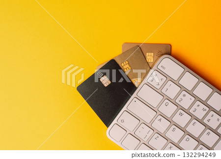 Set of multicolored contactless bank cards fan out beside a compact keyboard on a bright yellow desk, illustrating online payments, ecommerce, and cashless transactions Set of multicolored contactless bank cards fan out beside a compact keyboard on a bright yellow desk, illustrating online payments, ecommerce, and cashless transactions 132294249