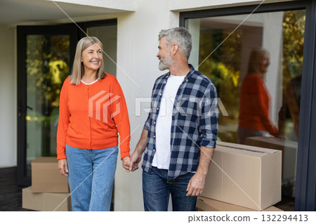 Senior couple holding hands together smiling with moving boxes in background Senior couple holding hands together smiling with moving boxes in background 132294413