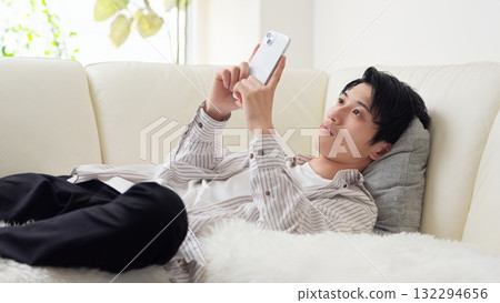 亞洲男子躺著看智慧型手機 132294656