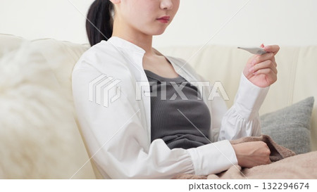 Asian woman measuring her temperature with a thermometer 132294674