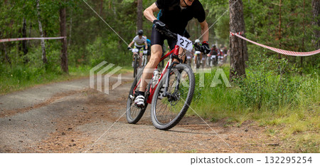 Leading athlete rides ahead group in forest during mountain bike competition 132295254
