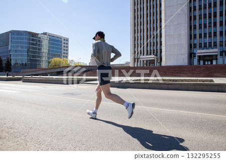 Male runner in cap running down deserted street marathon race 132295255
