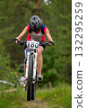 Female athlete riding bowed head on mountain bike in forest race 132295259