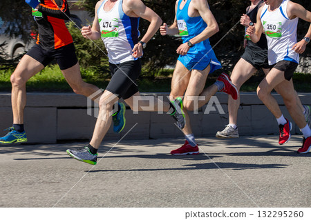 Five male athletes run marathon race down city street Five male athletes run marathon race down city street 132295260