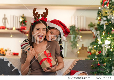 Festive Family Bonding. Mother and daughter sharing a Christmas gift with joy. Festive Family Bonding. Mother and daughter sharing a Christmas gift with joy. 132295453