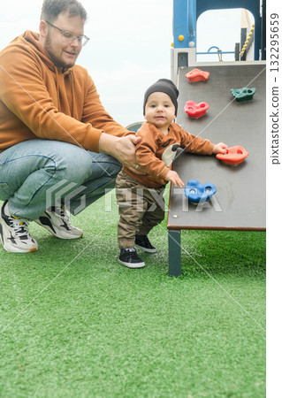 Father Assisting Toddler on Playground Climbing Wall 132295659