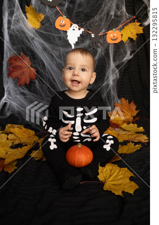 Baby in Skeleton Costume with Pumpkin and Leaves Baby in Skeleton Costume with Pumpkin and Leaves 132295815
