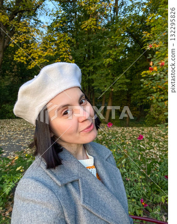 Woman in Gray Coat and Beret Smiling in Autumn Park Woman in Gray Coat and Beret Smiling in Autumn Park 132295826