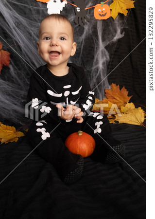 Baby in Skeleton Costume with Pumpkin and Leaves 132295829