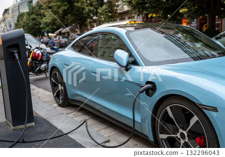 A plug-in sports car parked and connected to a charging station: the charging connector is highlighted. A concept for alternative mobility with a low environmental impact. 132296043