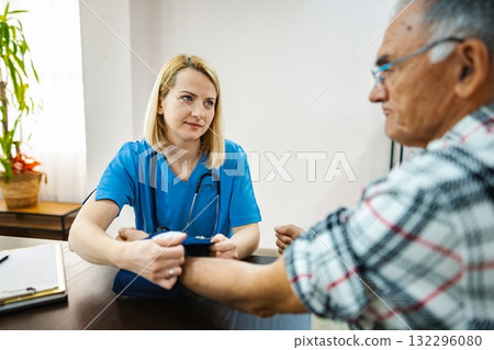 Caring nurse assists elderly man during a check-up Caring nurse assists elderly man during a check-up 132296080