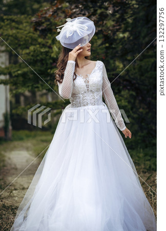 Elegant Bride in a Flowing White Gown Surrounded by Lush Greenery Elegant Bride in a Flowing White Gown Surrounded by Lush Greenery 132297756