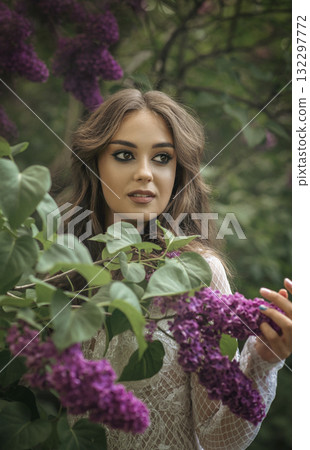 portrait of beautiful girl in white dress with long hair in garden among blooming lilac portrait of beautiful girl in white dress with long hair in garden among blooming lilac 132297772