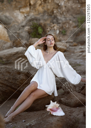 Young woman in summer white dress sits on rocks Young woman in summer white dress sits on rocks 132297805
