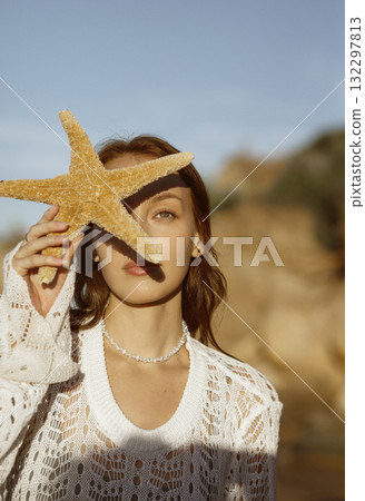 close up of beautiful young girl, starfish near her face 132297813