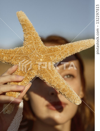 close up of beautiful young girl, starfish near her face close up of beautiful young girl, starfish near her face 132297815