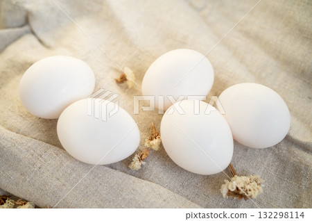 white eggs in a cardboard box, 10 pieces, on a surface made of natural materials. 132298114