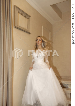 beautiful blonde bride walking down the stairs in the hotel. in a long wedding dress 132298211