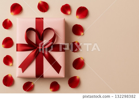 Pink gift box with red ribbon shaped into heart, surrounded by rose petals, copy space. Pink gift box with red ribbon shaped into heart, surrounded by rose petals, copy space. 132298382