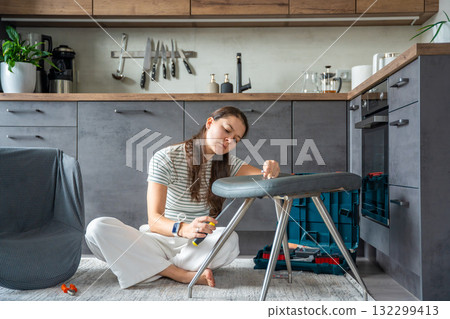 Frustrated young woman trying to assemble a chair with tools on the floor. Concept of difficulty and struggle in do it yourself project. Frustrated young woman trying to assemble a chair with tools on the floor. Concept of difficulty and struggle in do it yourself project. 132299413