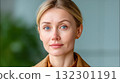A woman with striking blue eyes and light blonde hair stands confidently in a brightly lit space 132301191
