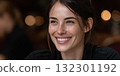 Woman with brown hair smiles warmly while sitting at a table in a bustling restaurant setting 132301192