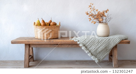A rustic bench holds a basket of pears and apples with a vase of dried flowers, embodying autumn elegance and cozy decor A rustic bench holds a basket of pears and apples with a vase of dried flowers, embodying autumn elegance and cozy decor 132301247