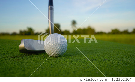 Golf clubs and balls on a green lawn in a beautiful golf course with morning sunshine. 132302104