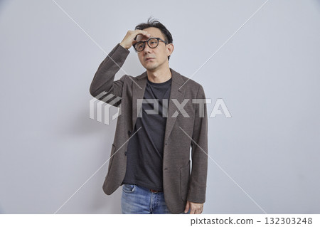 Portrait of stressed Japanese businessman in suit having headache on grey background. Portrait of stressed Japanese businessman in suit having headache on grey background. 132303248