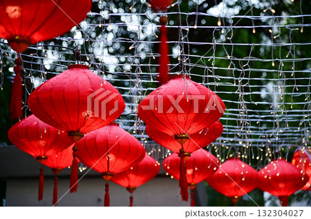 Close-up of the traditional Chinese red lantern with outdoor starry solar string lights. Big red lantern. Festive decoration. Mid-autumn festival, Chinese New Year decoration for celebration. Close-up of the traditional Chinese red lantern with outdoor starry solar string lights. Big red lantern. Festive decoration. Mid-autumn festival, Chinese New Year decoration for celebration. 132304027