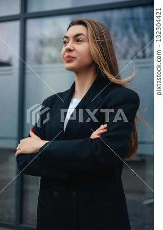 Confident Businesswoman Standing Outside a Modern Building With Arms Crossed During a Clear Daytime Confident Businesswoman Standing Outside a Modern Building With Arms Crossed During a Clear Daytime 132304421