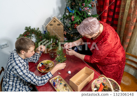 Senior woman spends time with family. Home decoration in December. Grandmother and Grandson Decorating Christmas tree 132306148