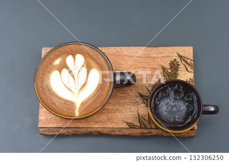 hot cappuccino coffee with latte art and cold ice water in cup on wooden board at table 132306250