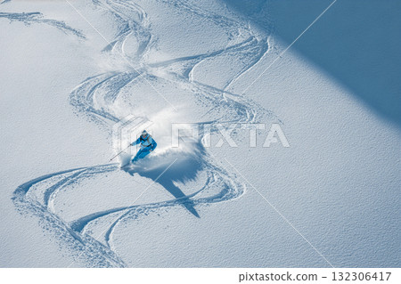 Skiing down powdery snow in pristine mountain terrain on a sunny winter day with clear blue skies and vibrant ski gear 132306417